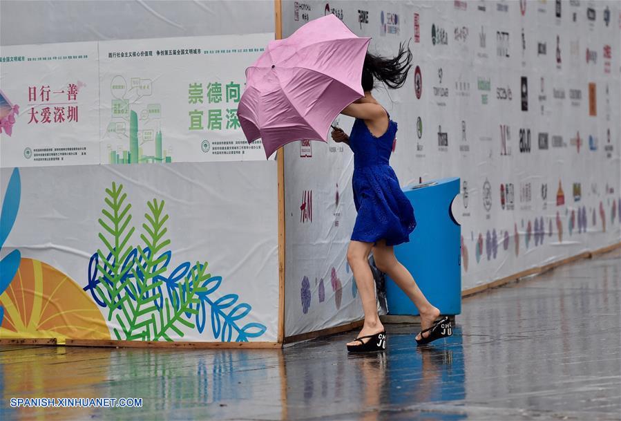 Una mujer intenta sostener una sombrilla en contra del viento en Shenzhen, en la provincia de Guangdong, en el sur de China, el 23 de agosto de 2017. (Xinhua/Mao Siqian)