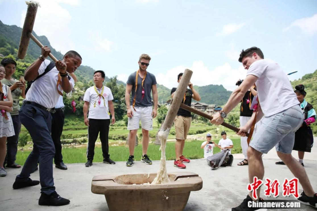 En julio de 2017, un grupo de 17 profesores y estudiantes de dos universidades de Alemania y Sudáfrica de visita en la provincia de Guizhou para un campamento de verano. En la imagen, estudiantes extranjeros experimentan la elaboración de ciba (pastel de arroz glutinoso) en una aldea miao. (CNS/ Huang Zhixin) 